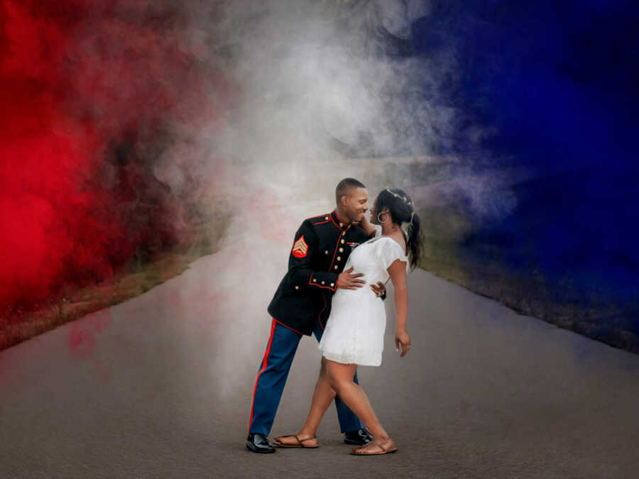 marine smiling while dipping wife outside in front of red, white, and blue background