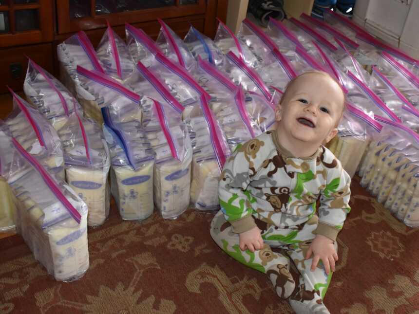 baby sitting next to bags of breast milk