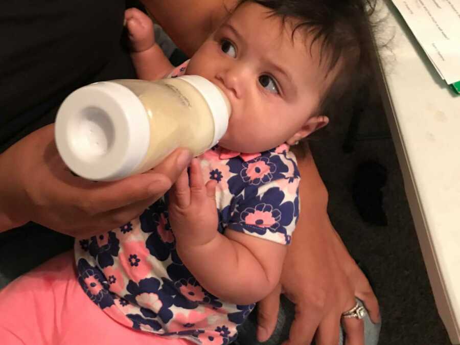baby girl drinking breast milk from bottle