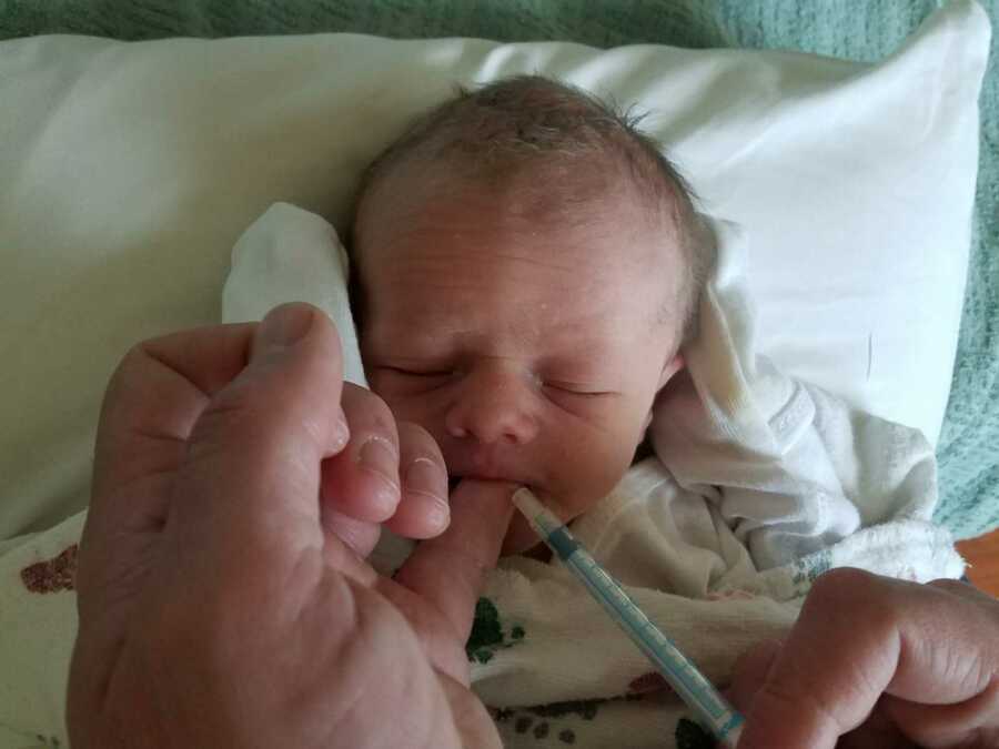 baby receiving milk through syringe