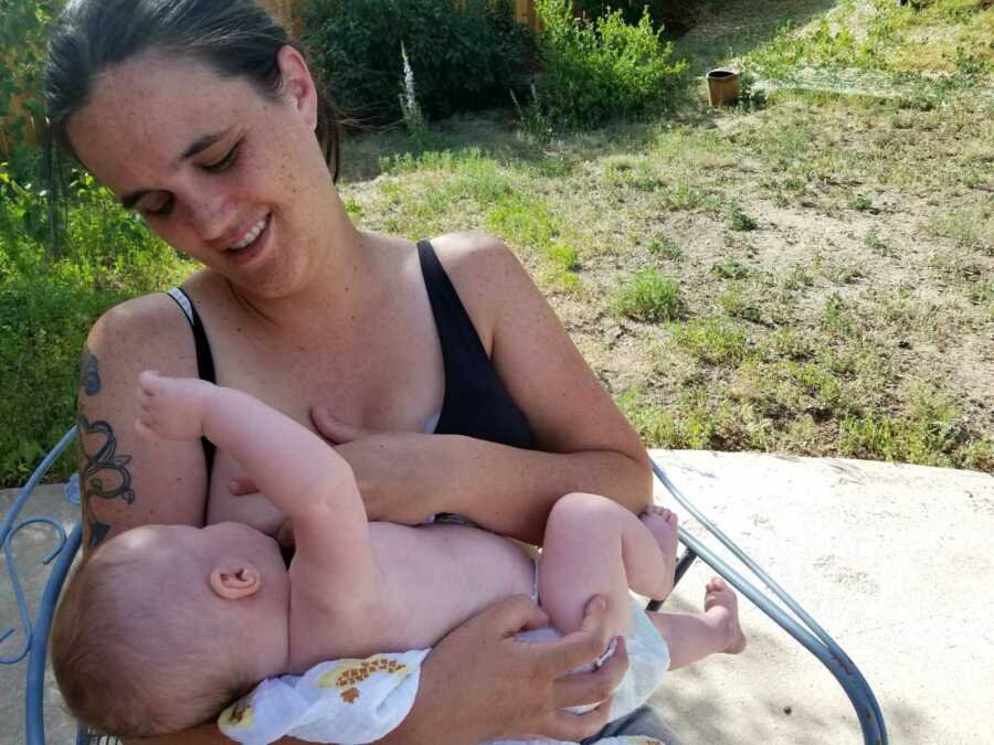 mom breastfeeding outside and smiling at baby