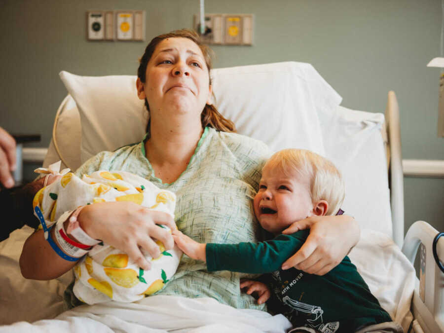 mom in hospital bed with son and newborn daughter