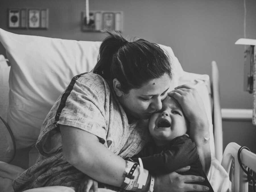 mom kissing crying son in hospital bed