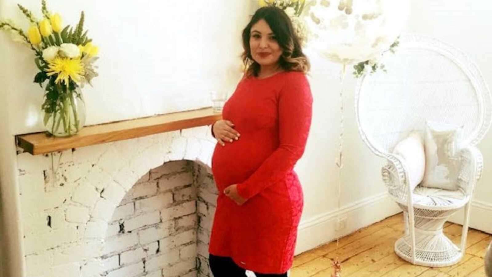 pregnant woman in red dress holding baby bump