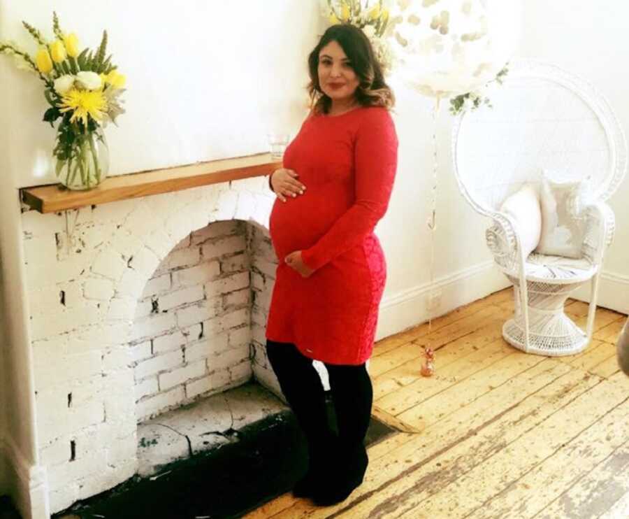 pregnant woman in red dress holding baby bump