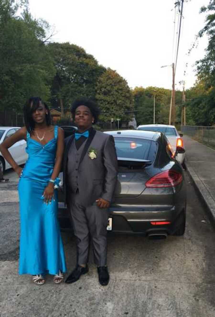 Teen prom dates standing in front of porsche 