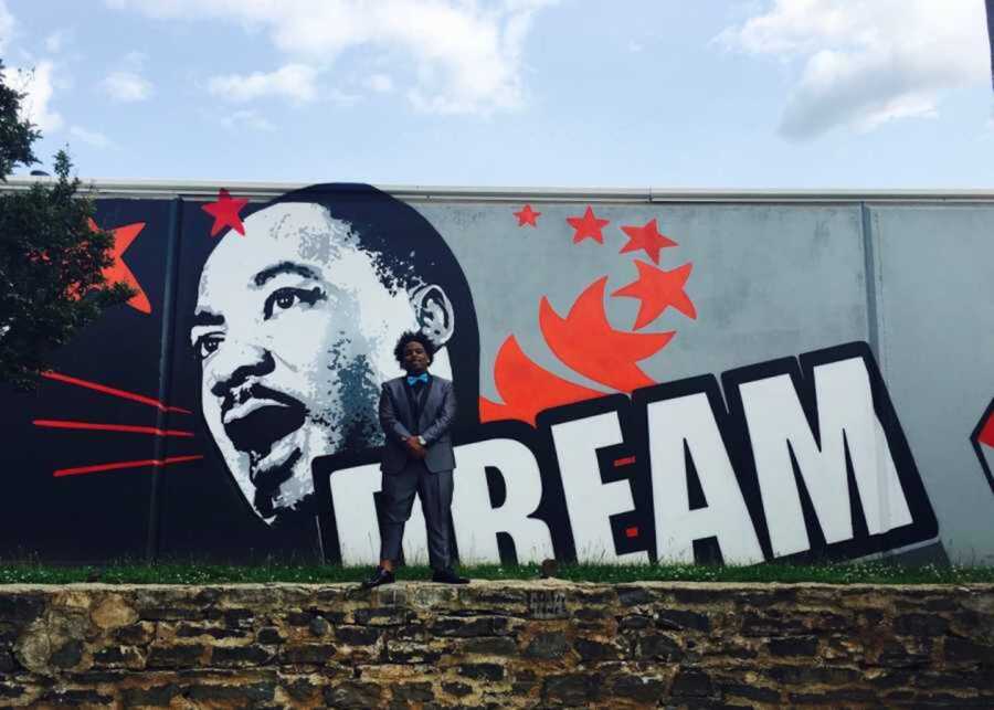 Teen boy standing in front of Atlanta MLK street art