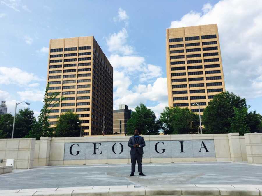 Teen in from suit standing in front of Georgia street sign