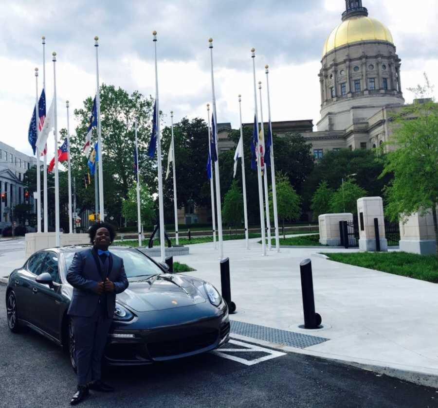 Teen boy in prom suit standing in front of porsche