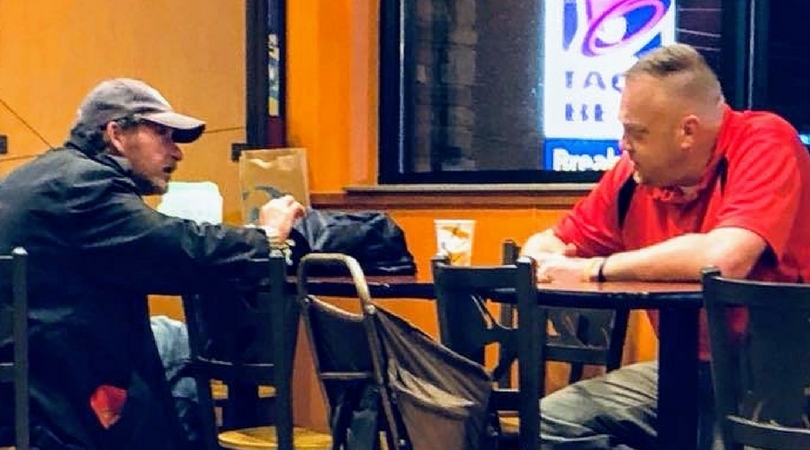 two men sitting at a table in Taco Bell