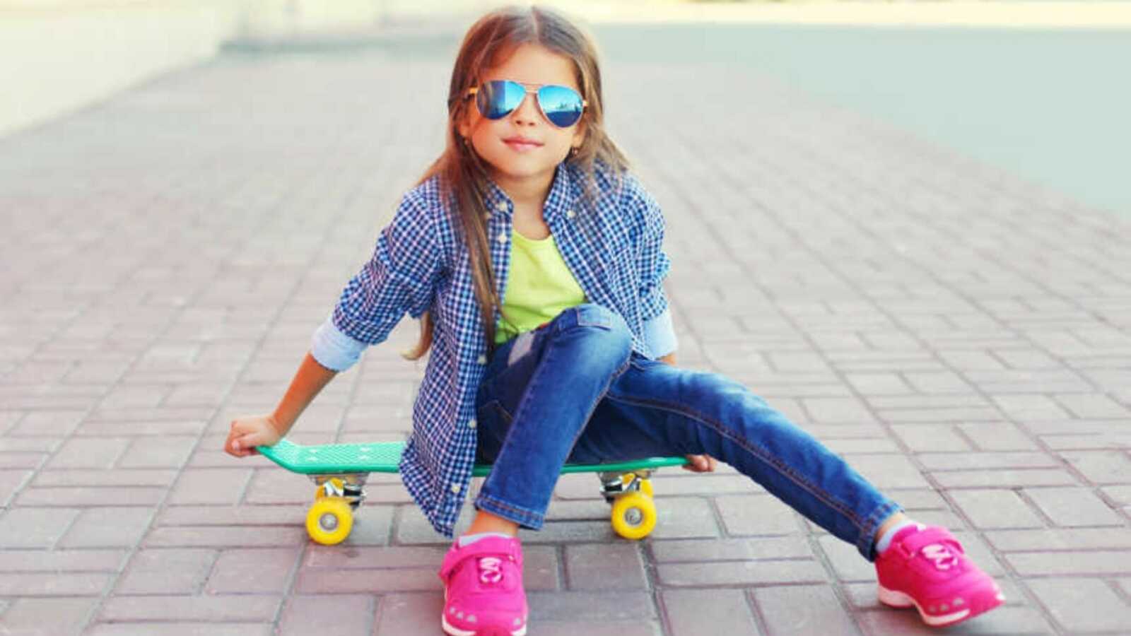 girl with sunglasses sitting on skateboard