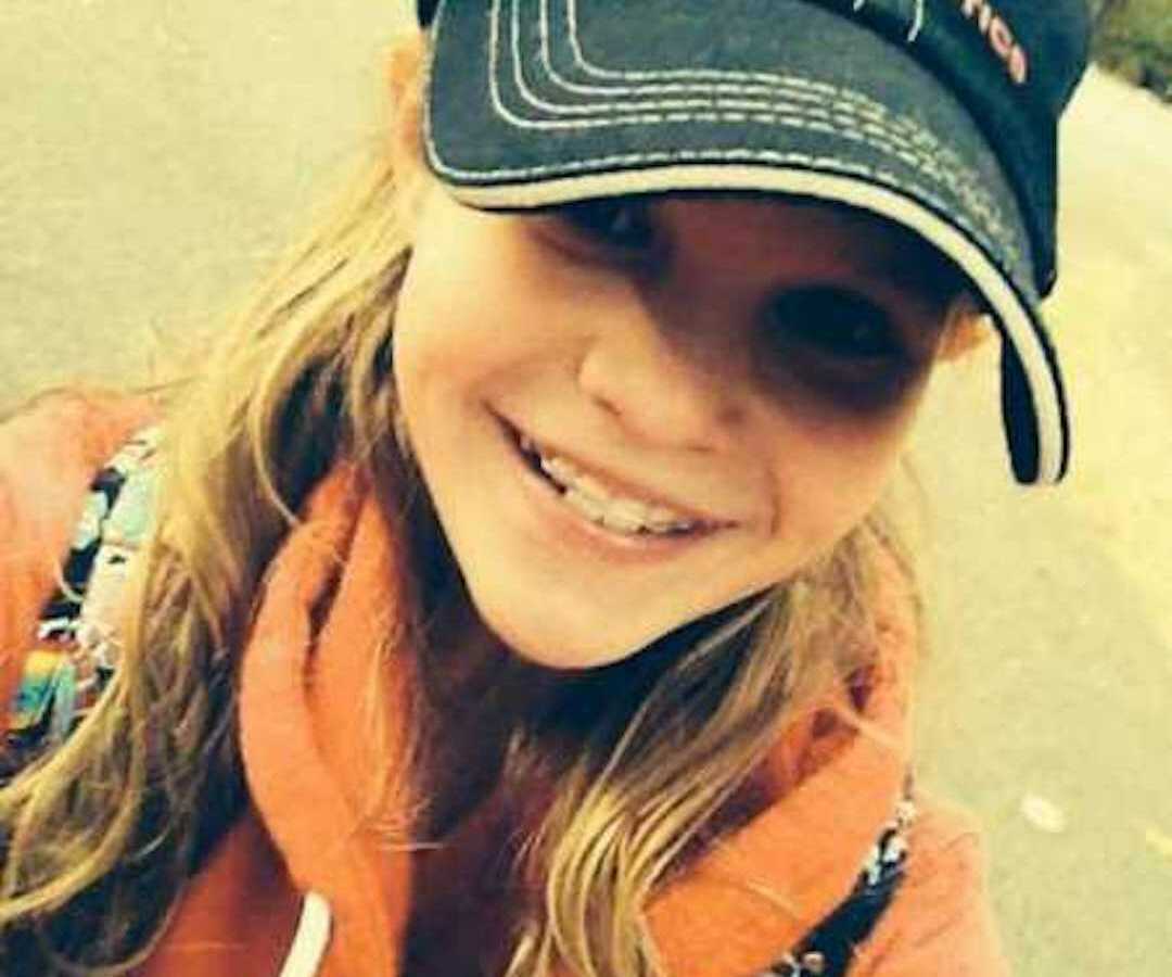 young teen girl smiling outside while wearing hat