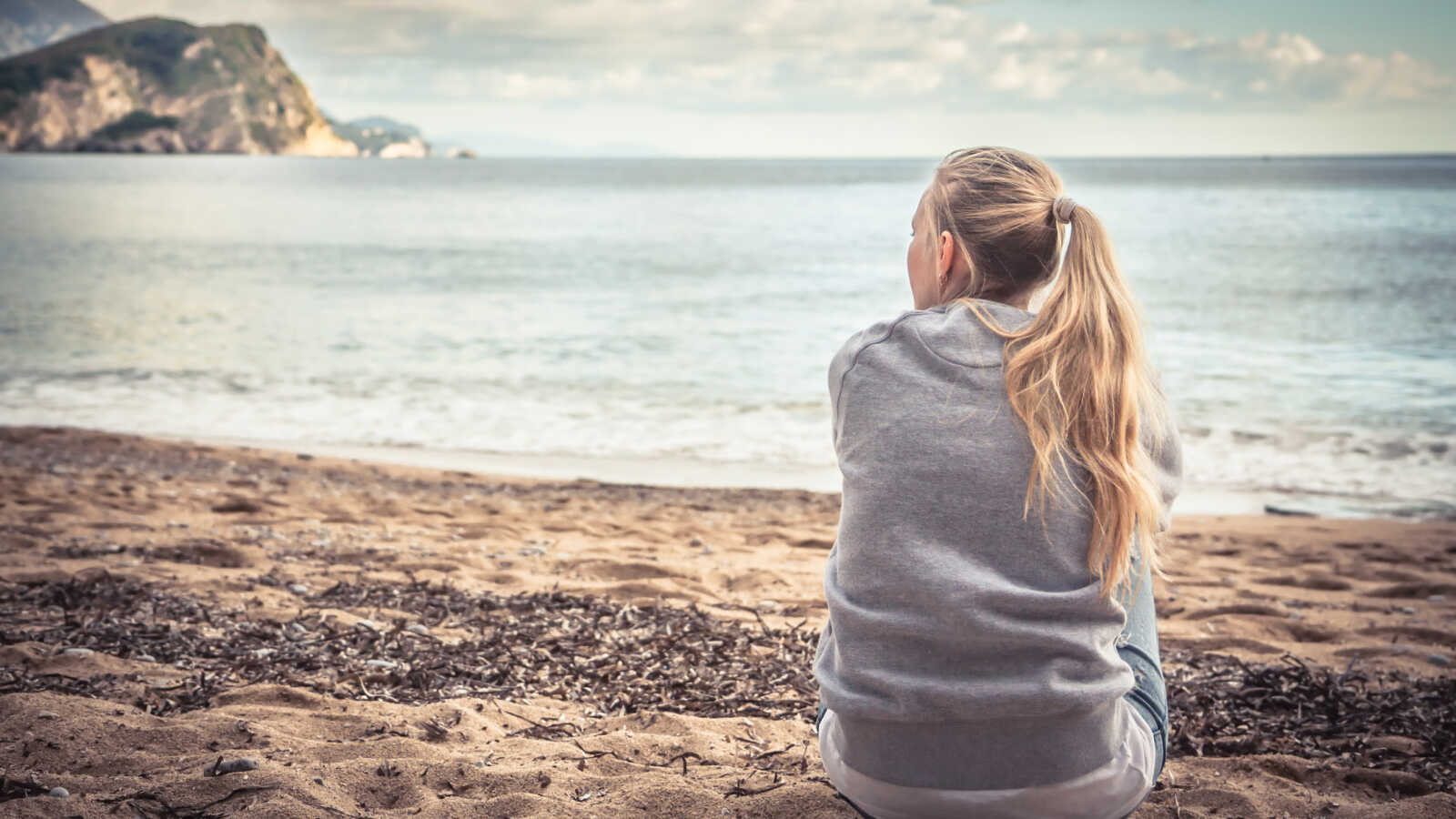 woman sitting on beach looking at ocean