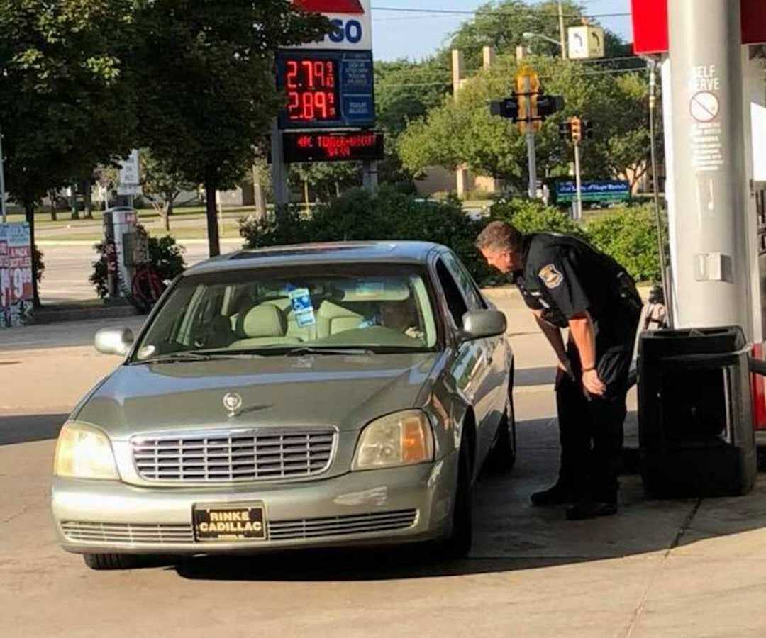 police officer standing at car door of elderly woman