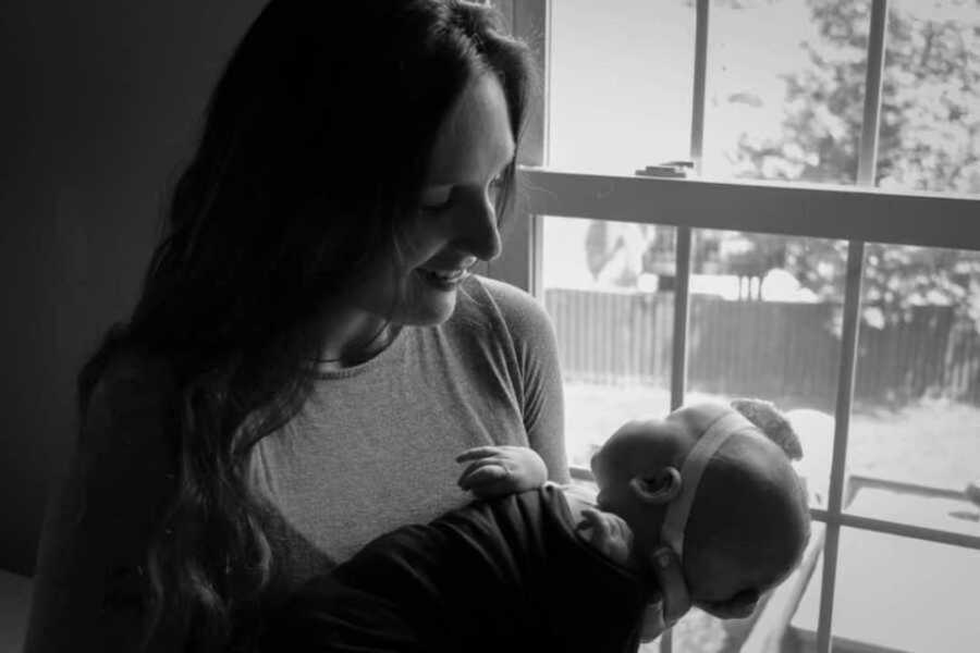 mom holding baby by window