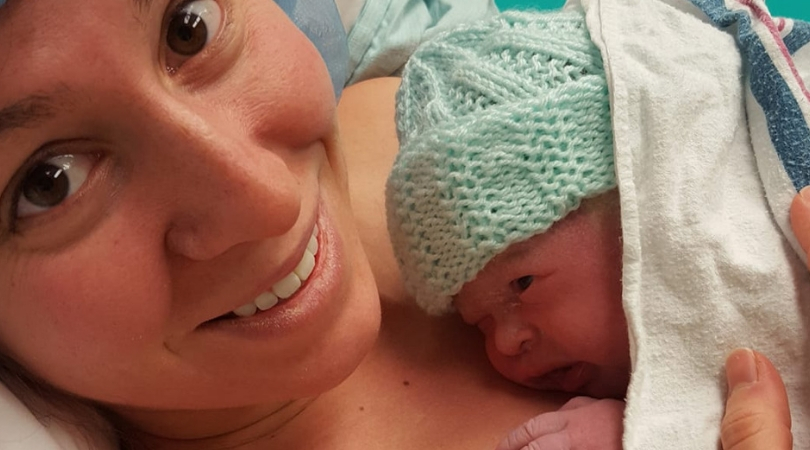 mom holding newborn baby in hospital bed
