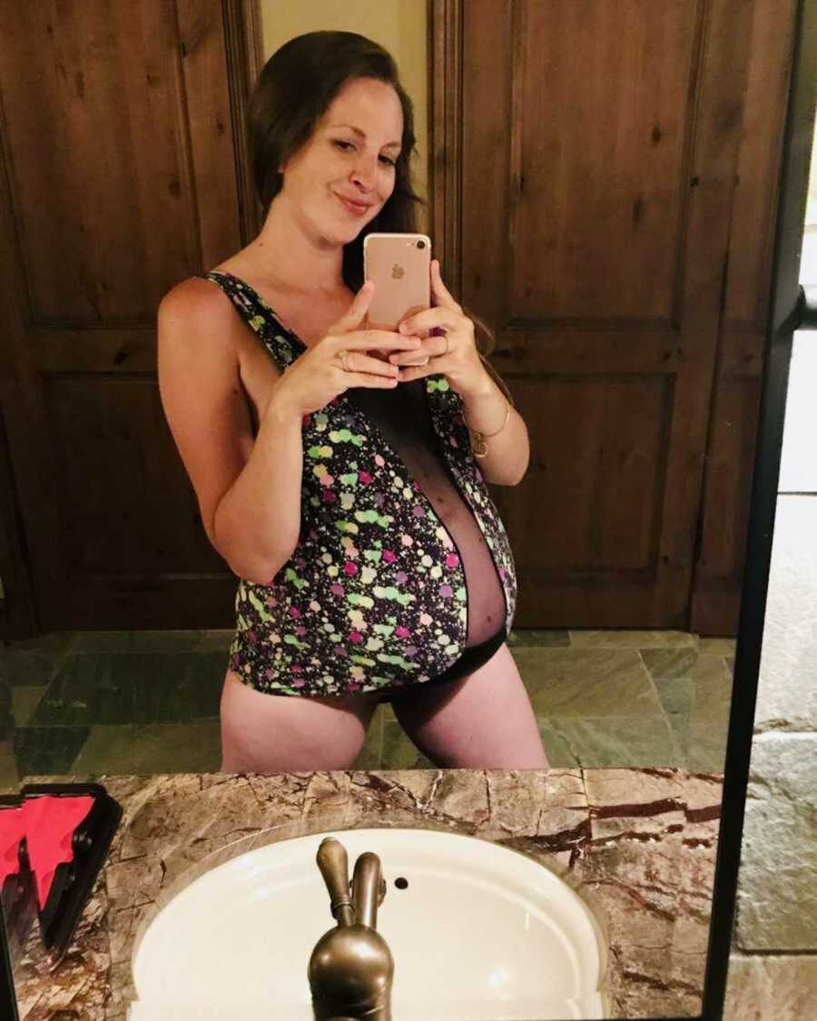 pregnant woman in swimsuit taking a mirror selfie