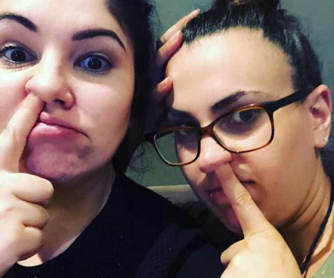 two women with their pointer fingers in their noses