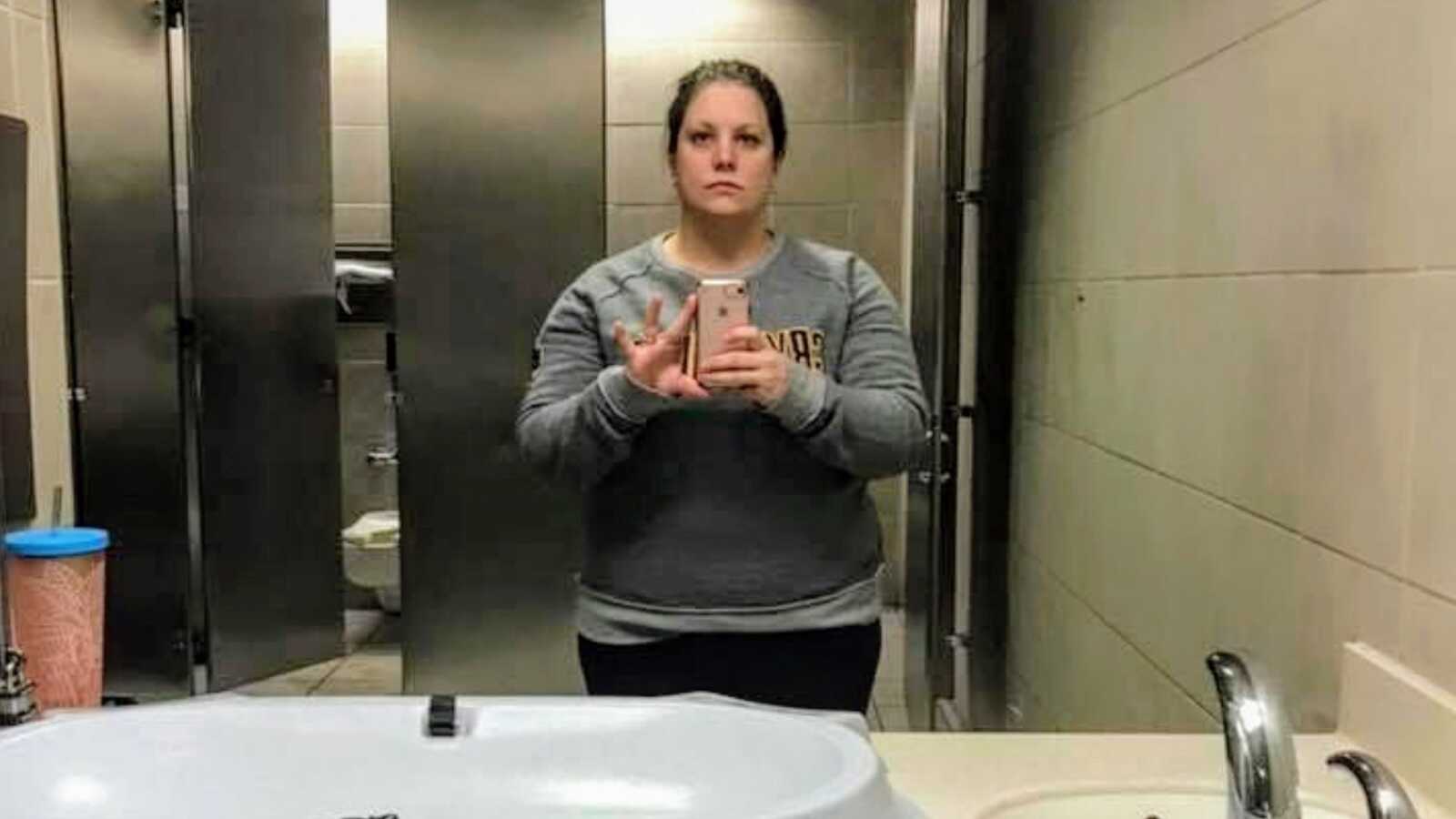 woman taking a selfie in airport bathroom
