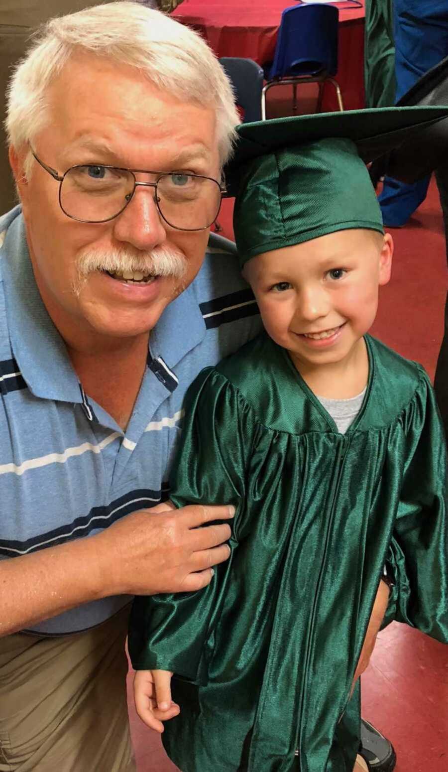 man stands with child in graduation cap and gown