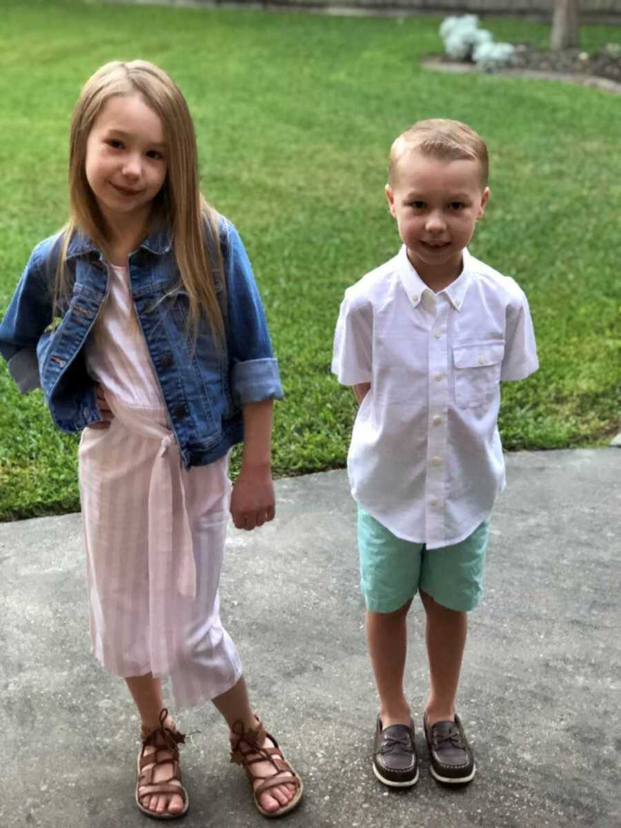 two young children standing outside in nice clothes