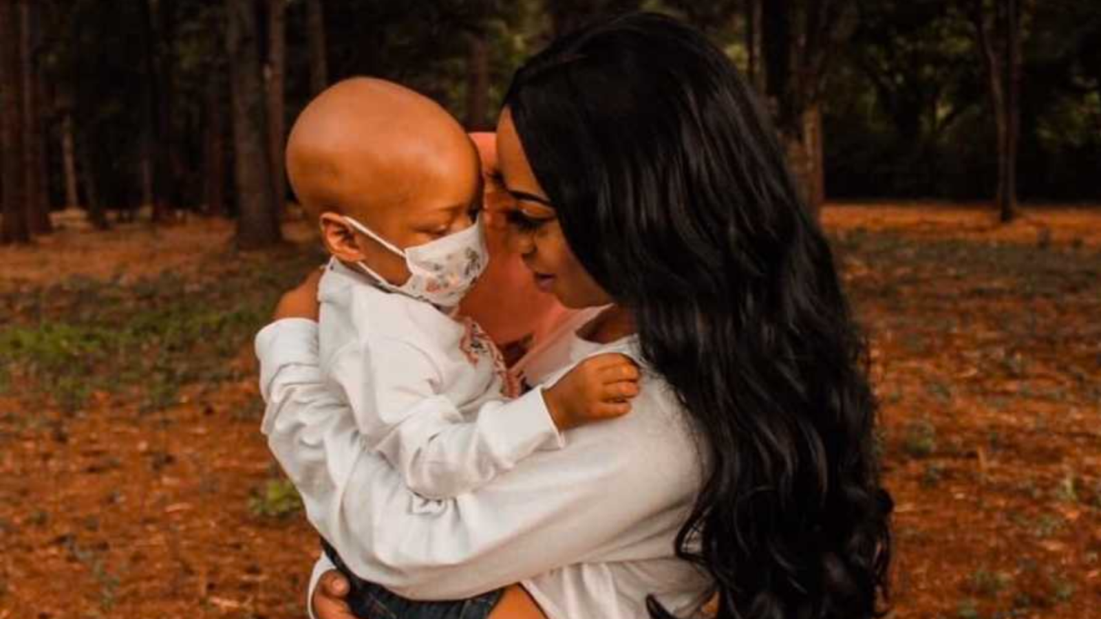 Mom holding sick, masked child