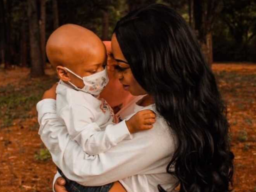 Mom holding sick, masked child