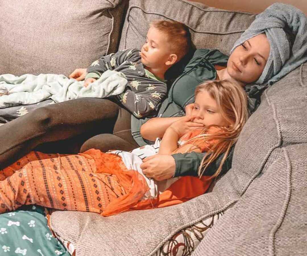 mom laying on couch with two kids