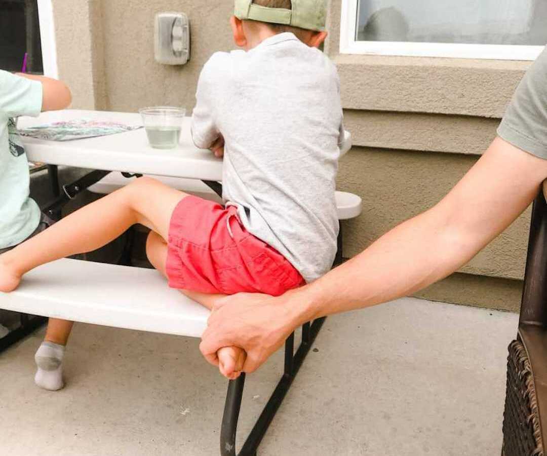dad holding son's foot while he sits at table