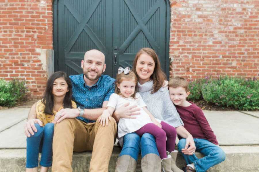 Smiling family sitting on sidewalk