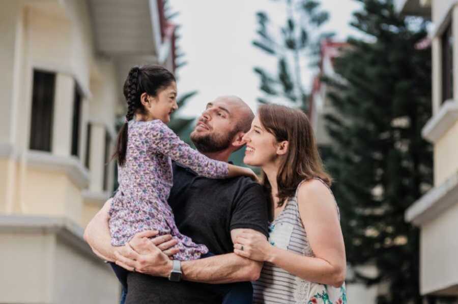 Adoptive mom and dad smiling at daughter