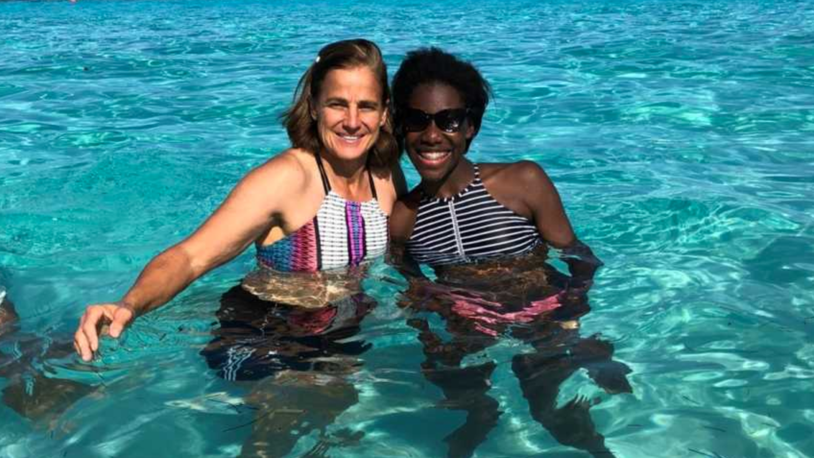 Adoptive mom and daughter swimming in clear blue water