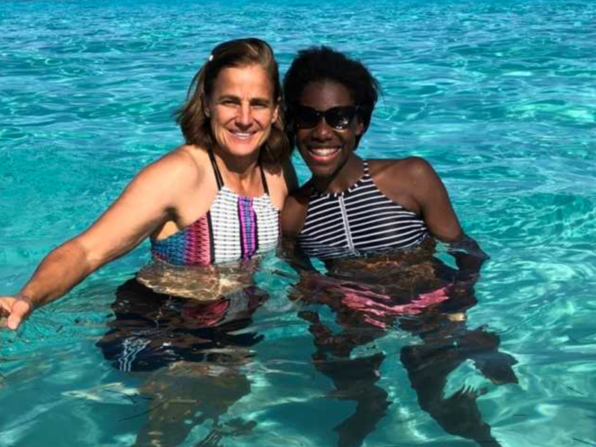 Adoptive mom and daughter swimming in clear blue water