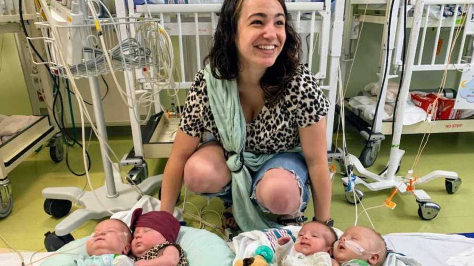 Woman smiling in hospital room with newborn quadruplets