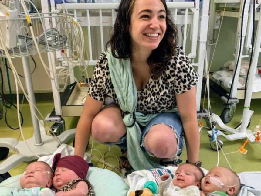 Woman smiling in hospital room with newborn quadruplets