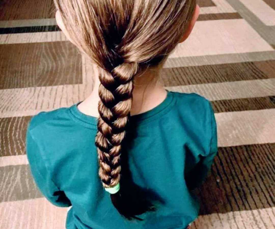 young girl sitting on floor with hair in long braid