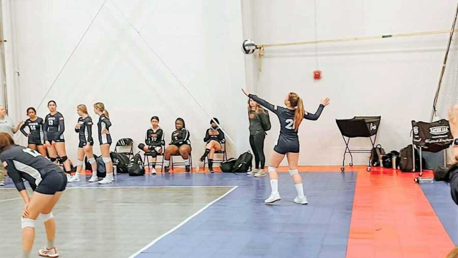 teen girl playing volleyball in a gym