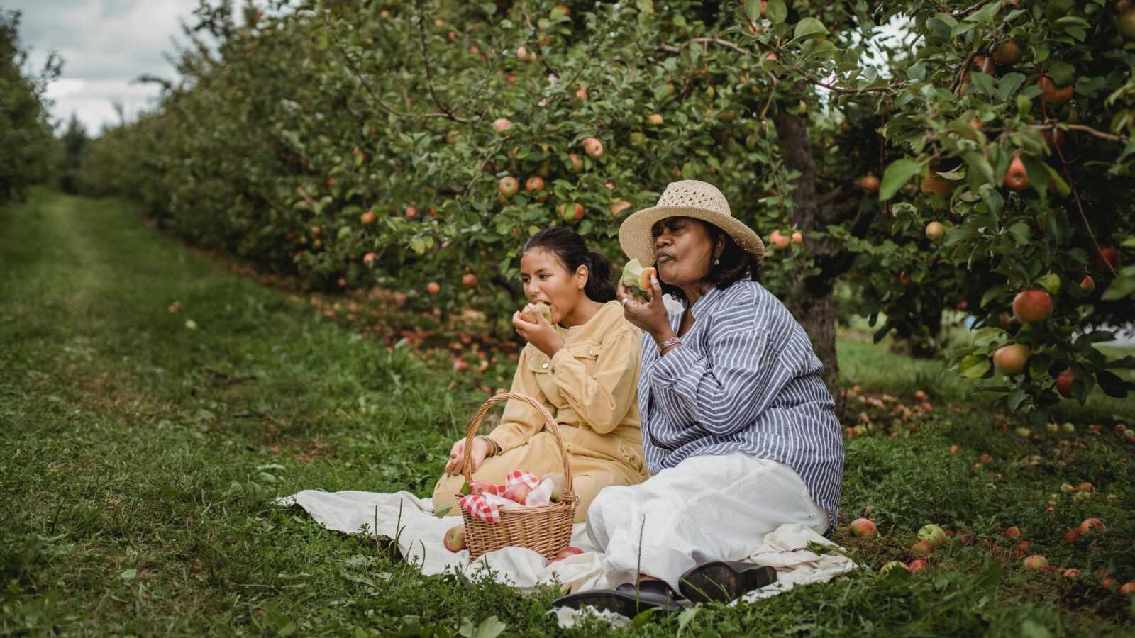 mom and daughter eating apples outdoors