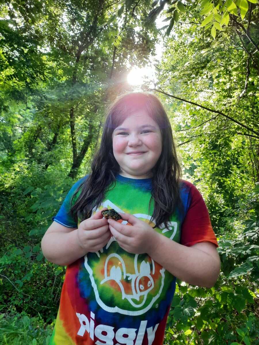 Girl in tie dye shirt holding baby turtle