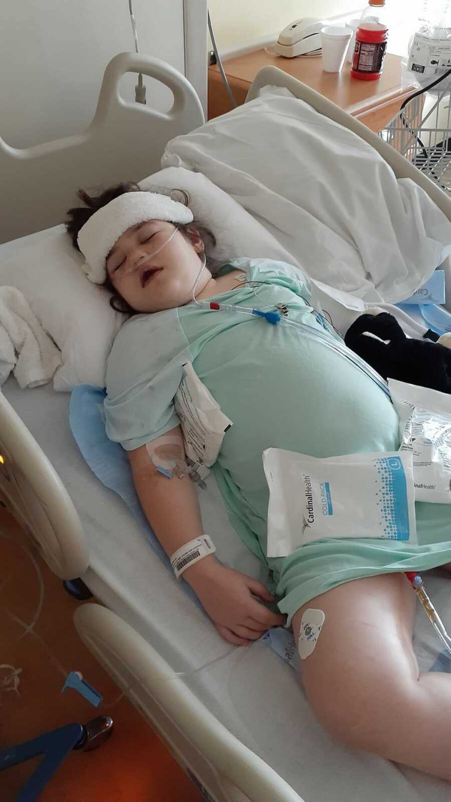 Girl lying in hospital bed with ice packs on stomach
