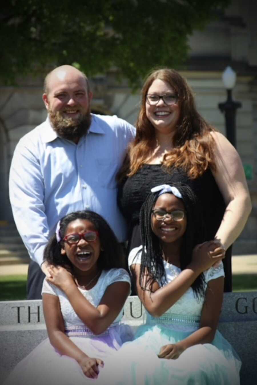 Adoptive family of four smiling into camera