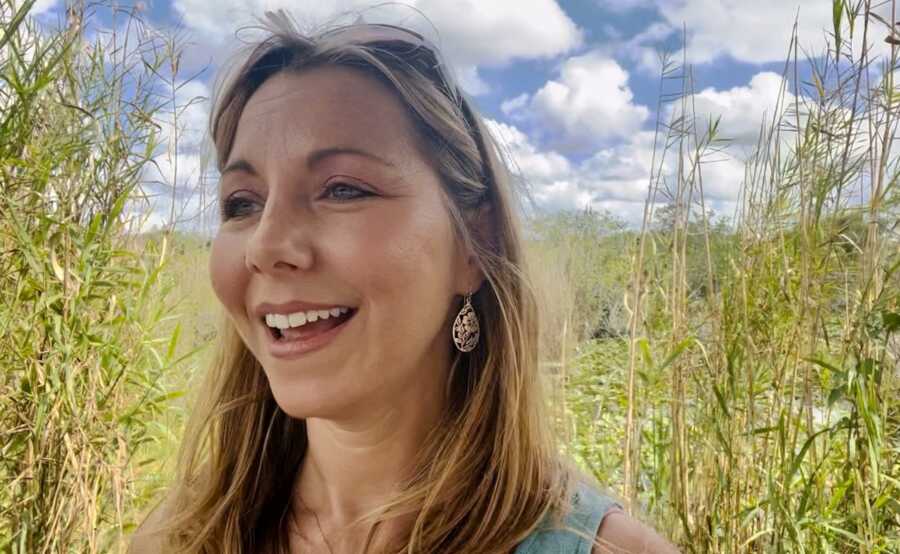 Blonde woman smiling inside green bush