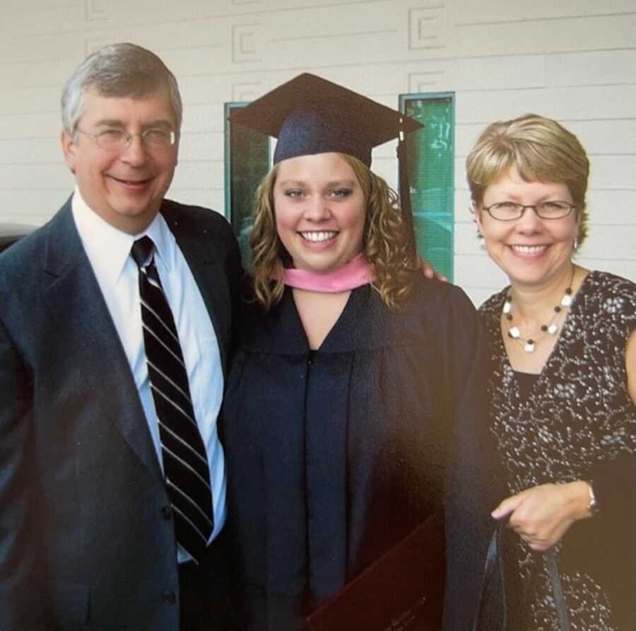 Adoptive parents smiling with college graduate