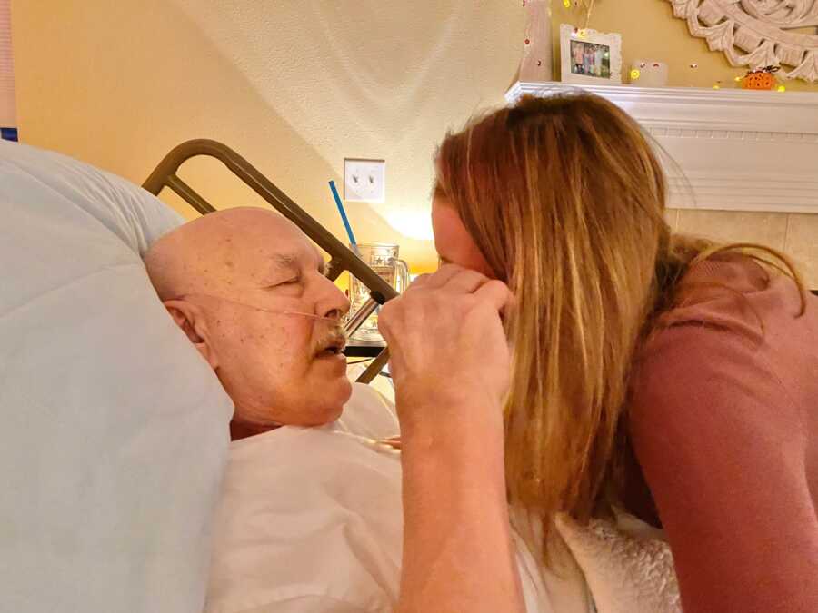 Daughter embracing sick father in hospital bed