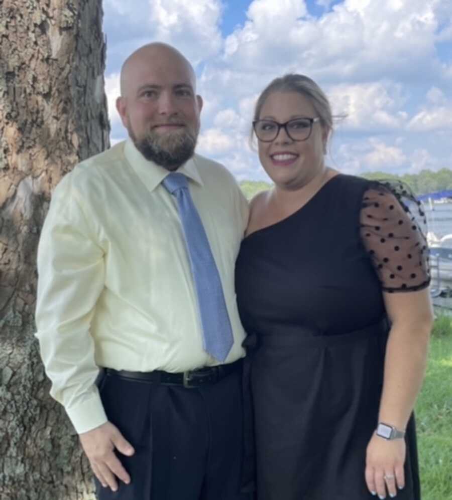 Husband and wife standing by tree