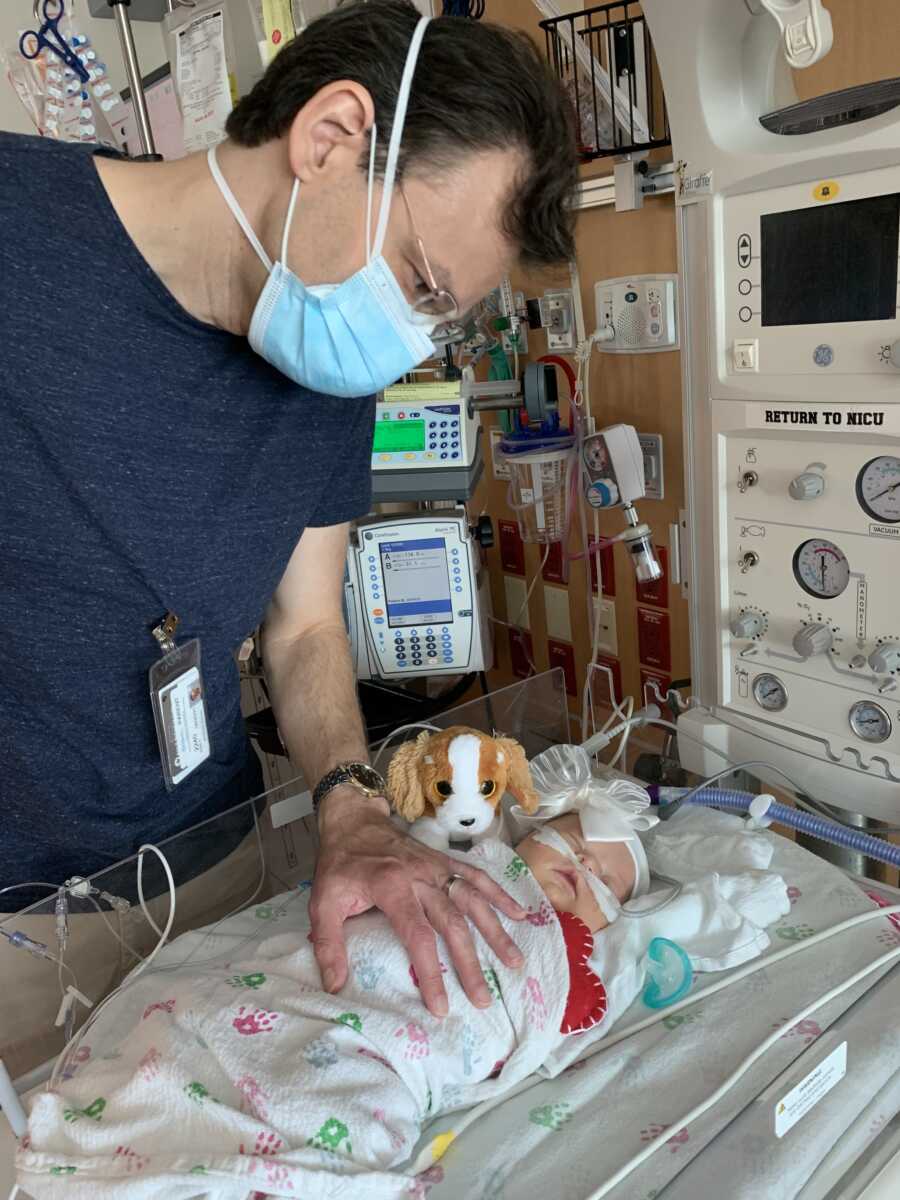 Dad embracing child with Down syndrome in hospital bed