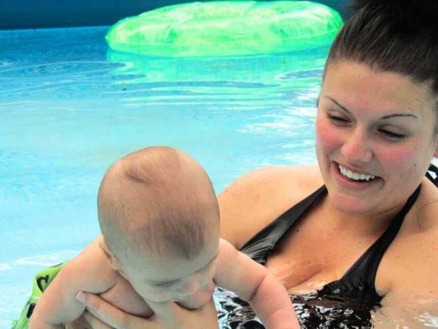 New mom and infant swimming in pool water