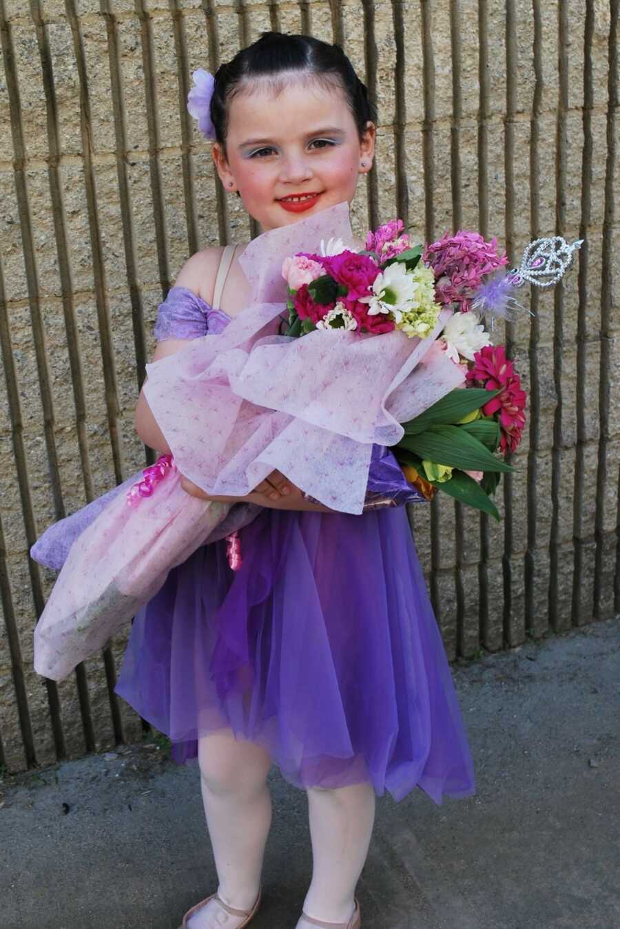 Girl in purple dance dress holding bouqet of flowers