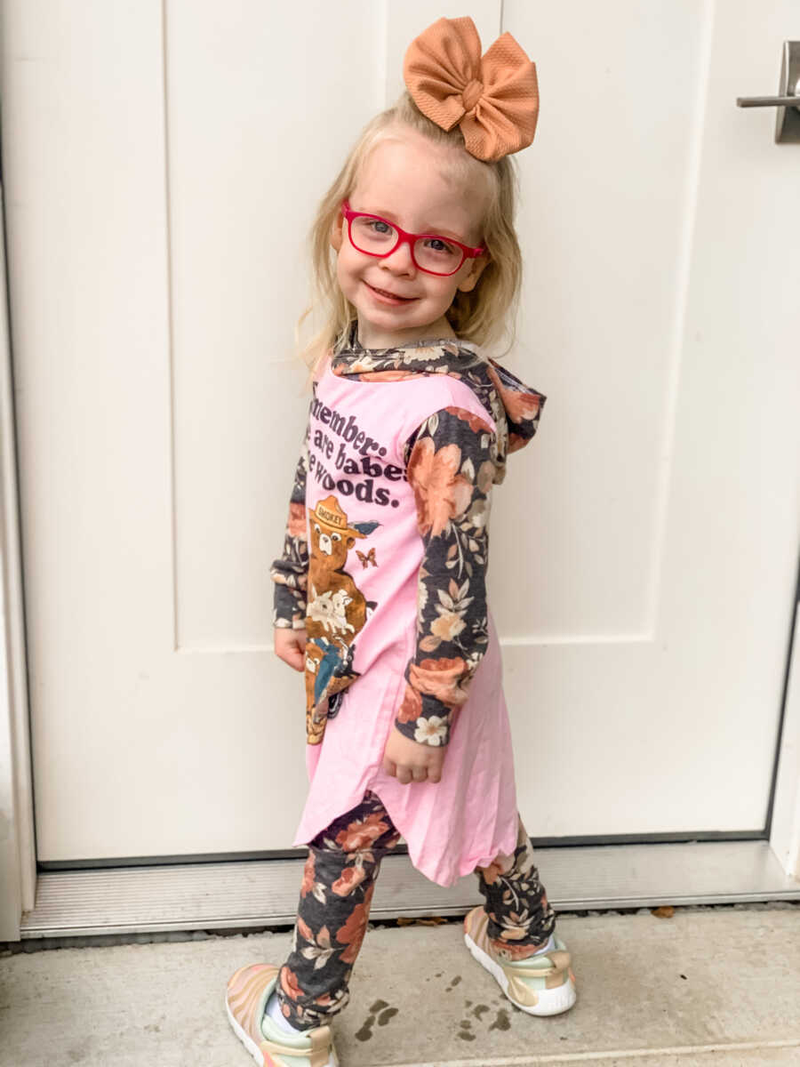 Little girl standing in front of white door in floral prints