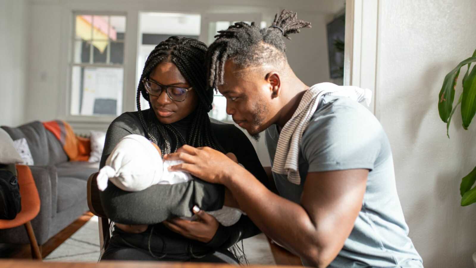 black couple staring at newborn baby in mom's arms
